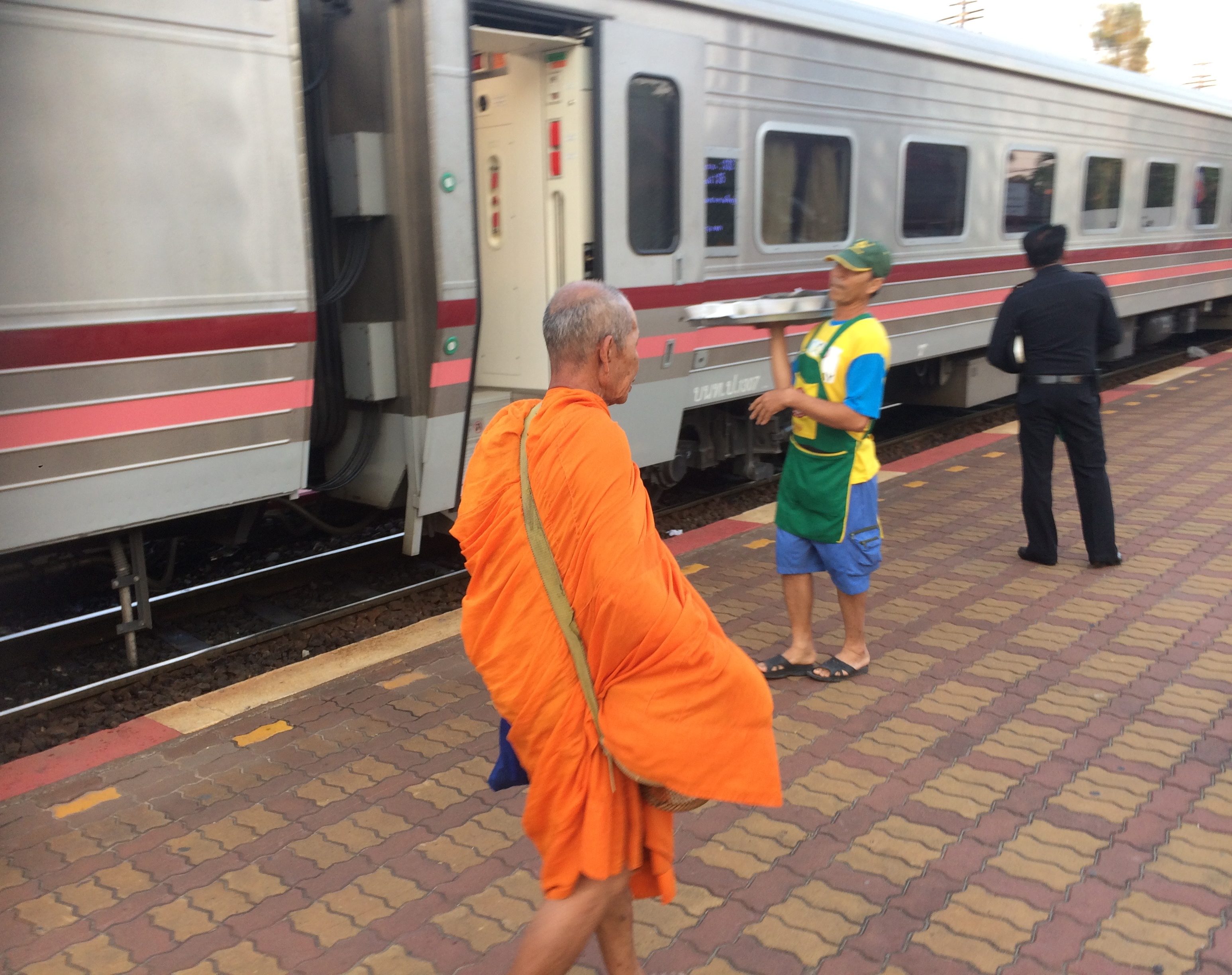 a man in an orange robe standing next to a train