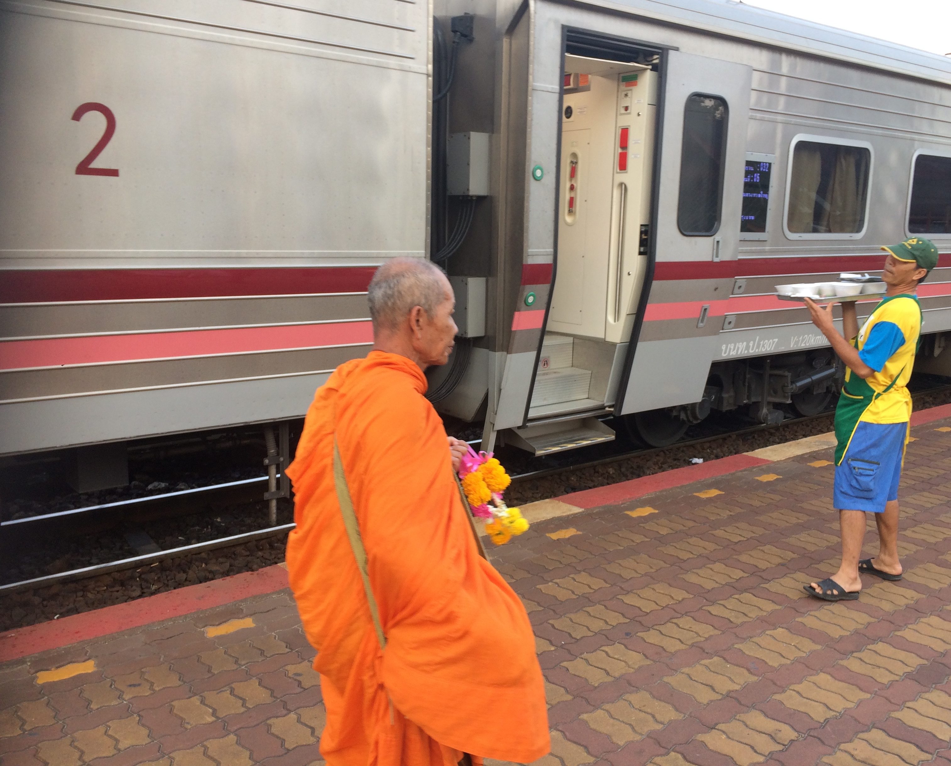 a man in orange robe standing next to a train