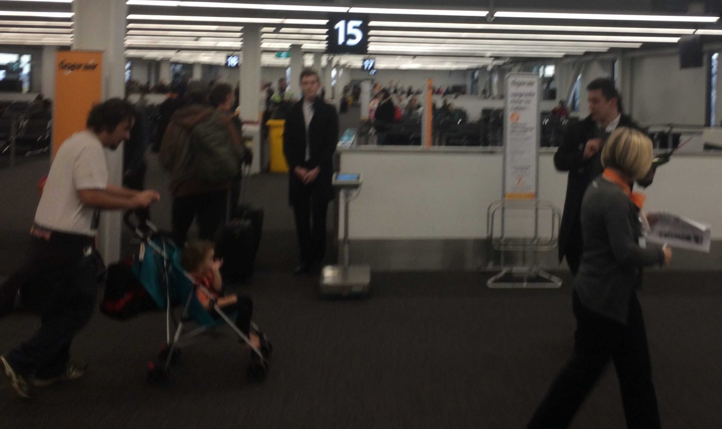 a man standing in an airport with a child in a stroller