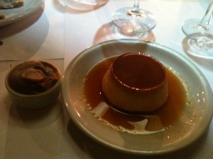 a flan on a plate with a bowl of liquid