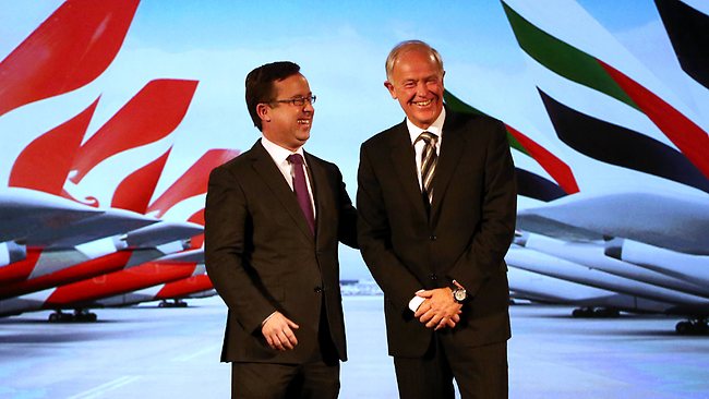 two men in suits standing in front of a screen with airplanes in the background