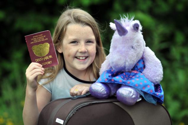 a girl holding a passport and a stuffed animal