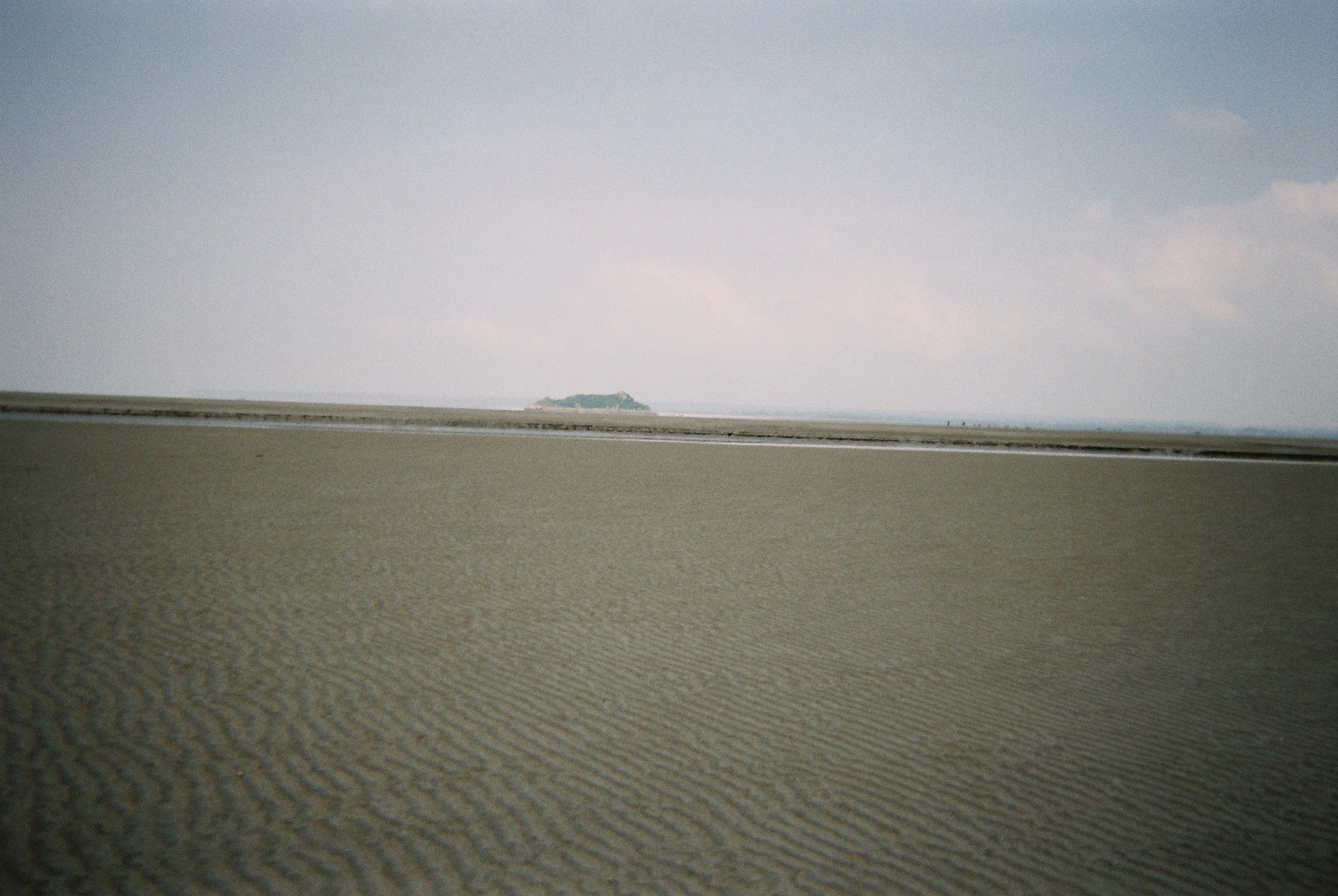 a large flat sand area with a small island in the distance