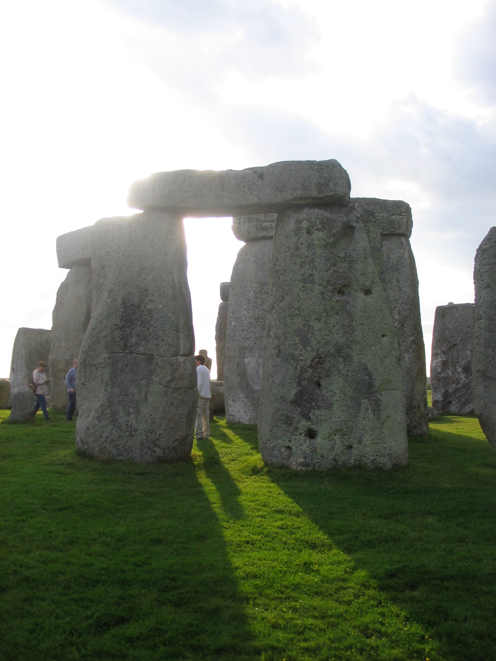 people standing in a grassy area with large rocks with Stonehenge in the background