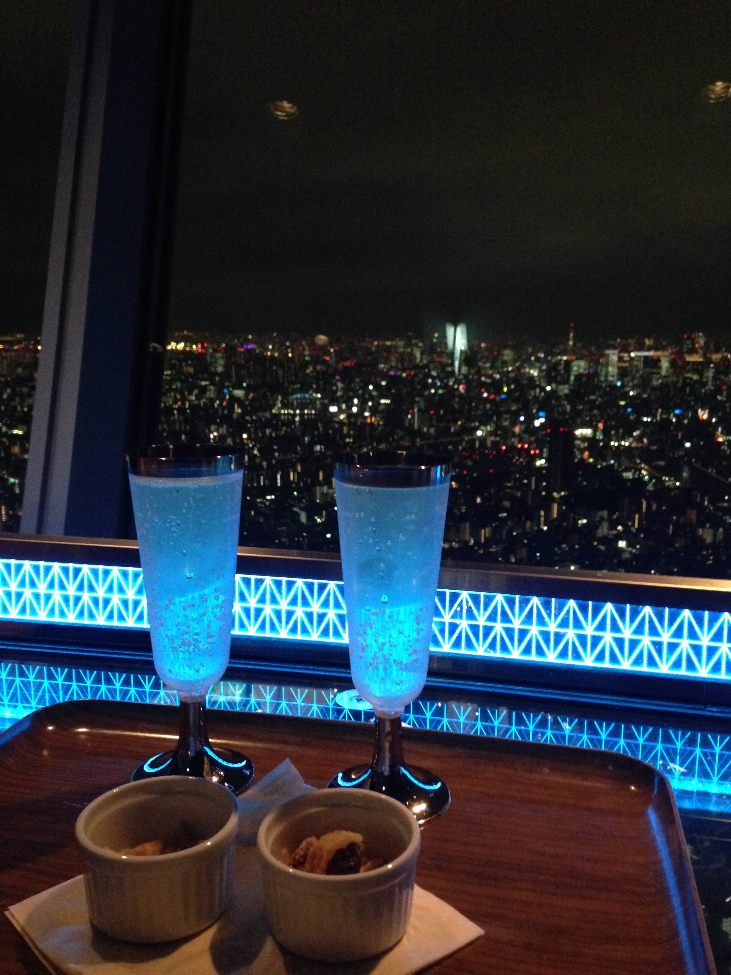 a two glasses of liquid on a table with a view of a city