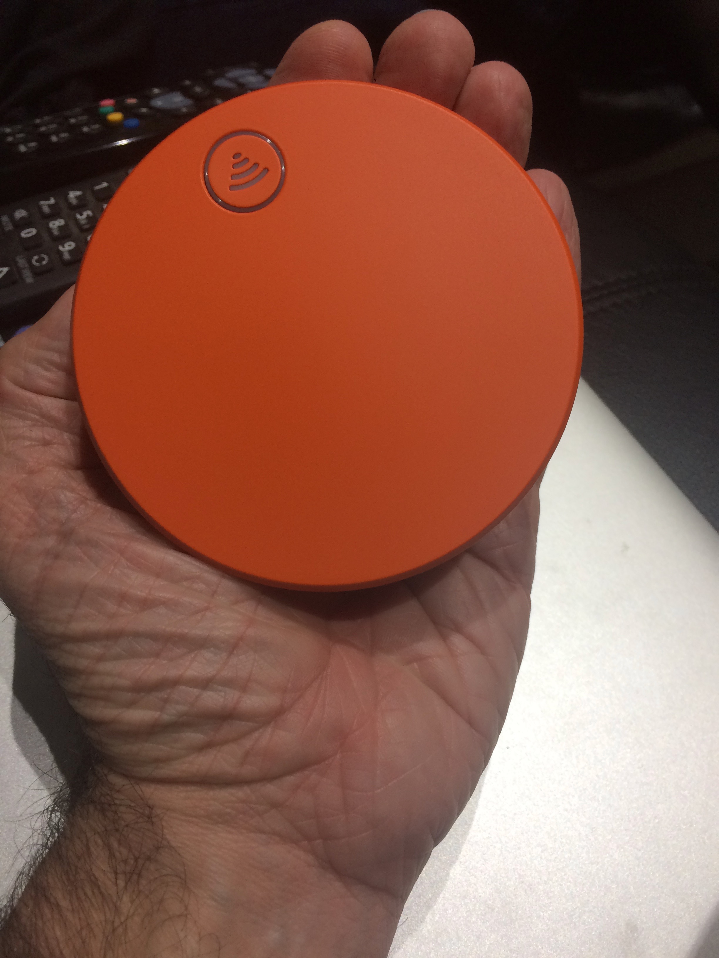 a hand holding an orange device