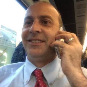 a man in a white shirt and red tie talking on a cell phone