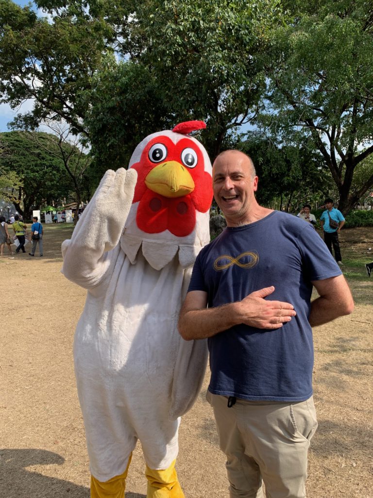 a man in a chicken garment with a person in a blue shirt