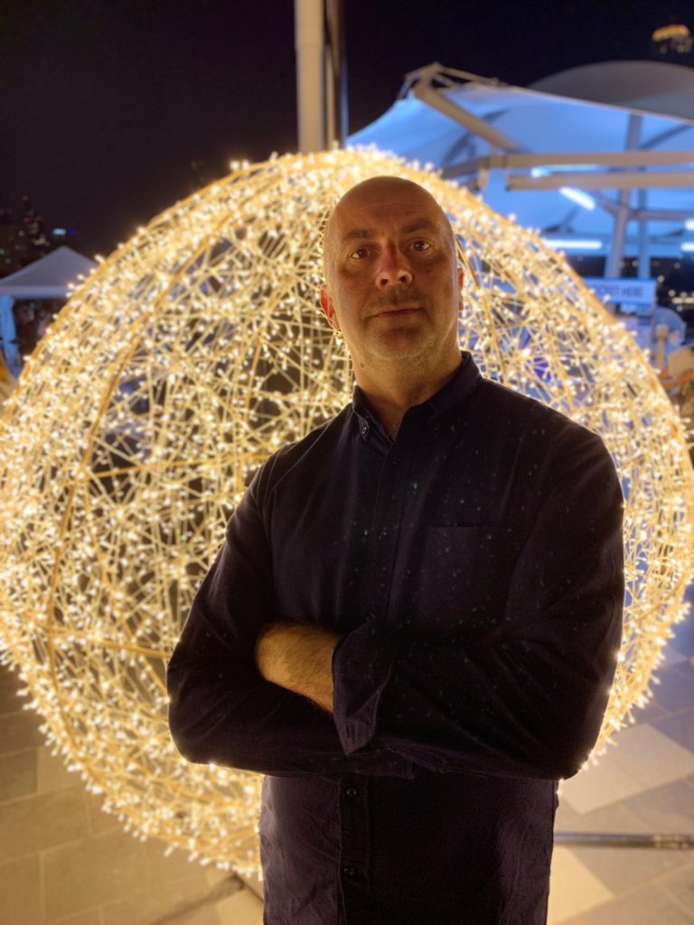 a man standing in front of a large sphere of lights