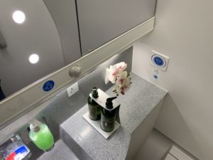 a bathroom sink with bottles of liquid and flowers