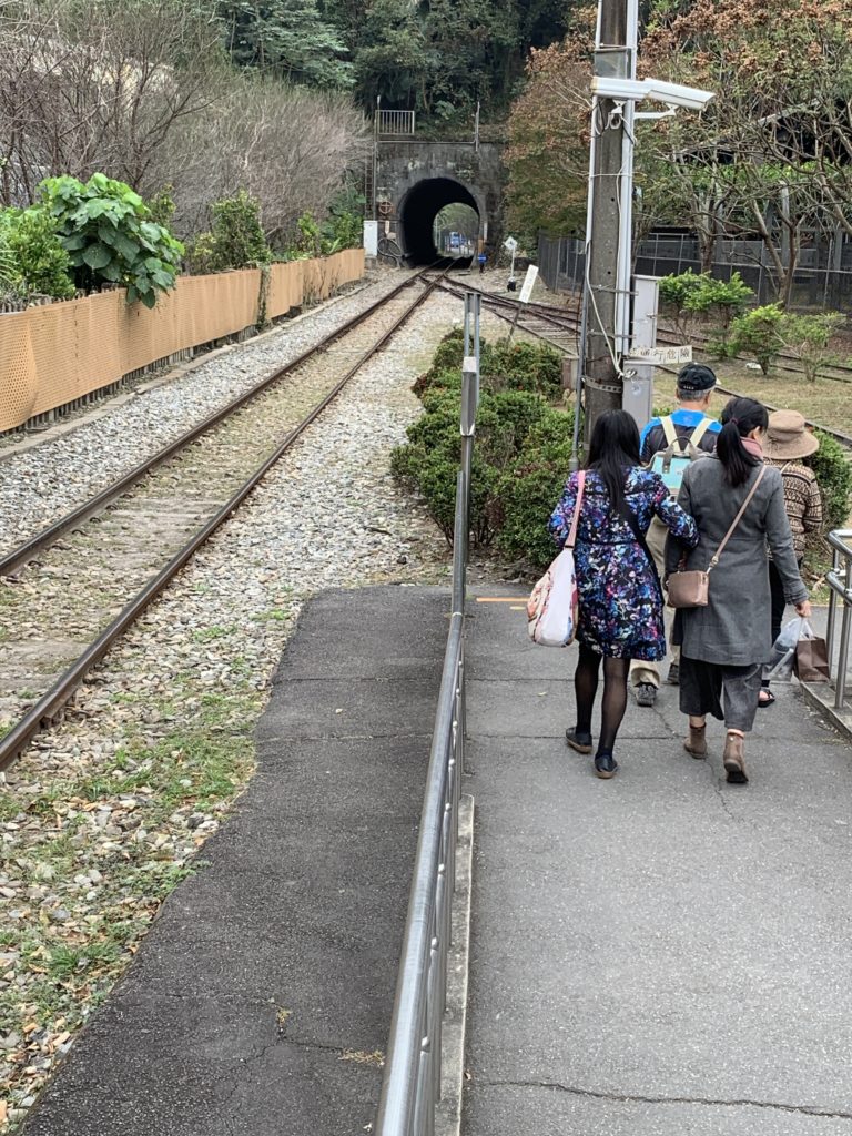 a group of people walking on a path next to a tunnel