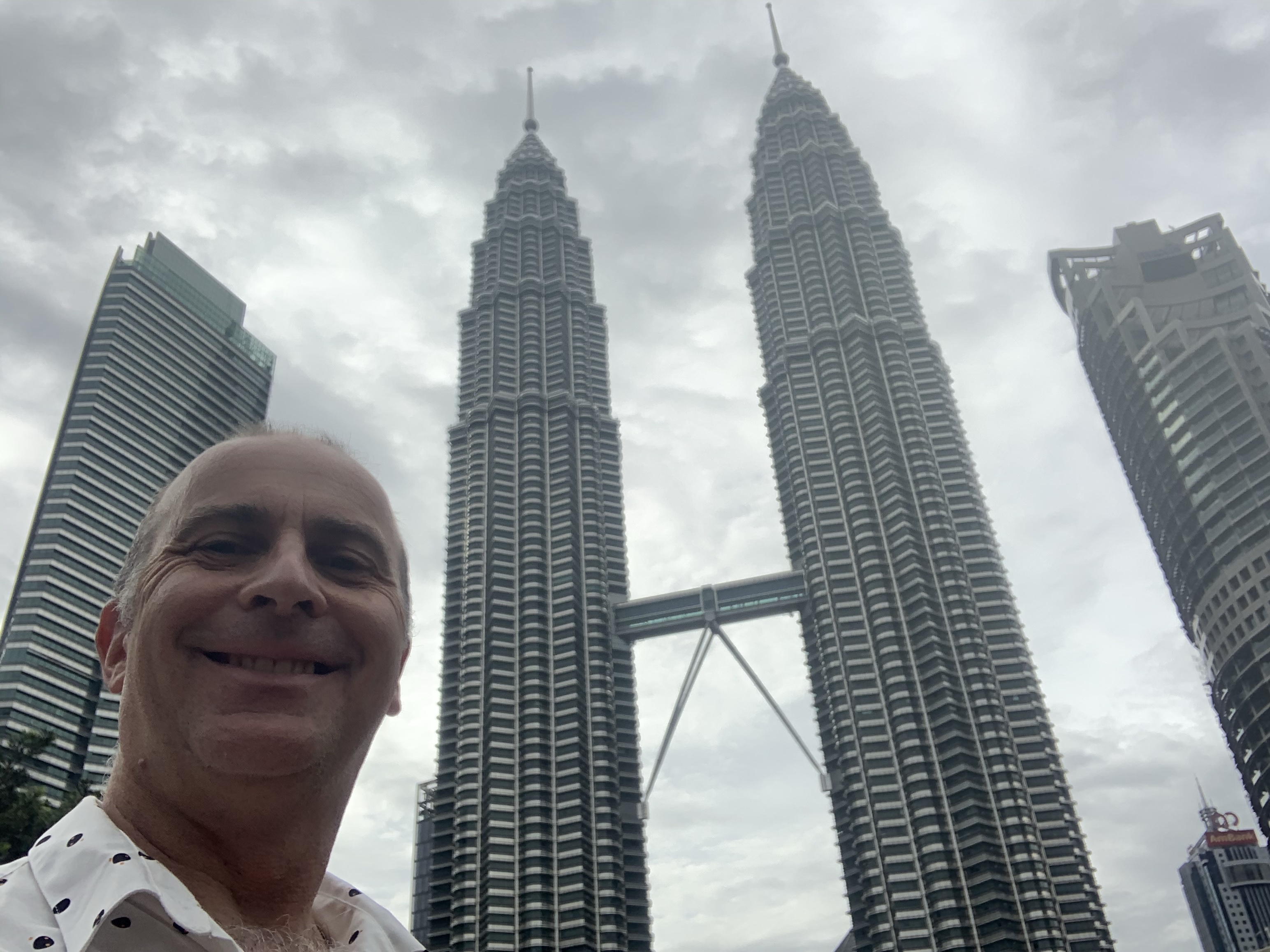a man taking a selfie in front of two tall buildings