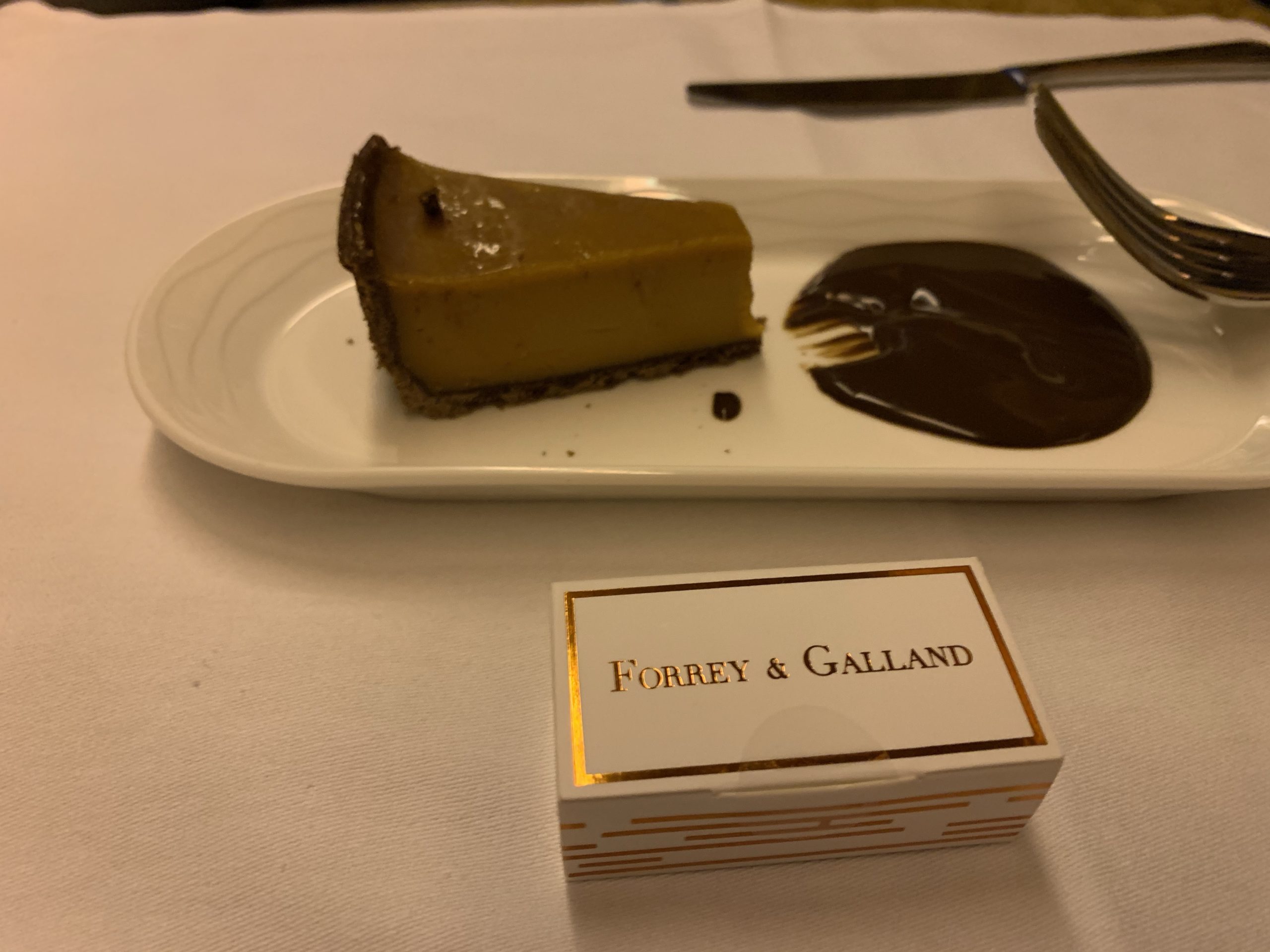 a slice of pie on a plate next to a box of chocolate sauce