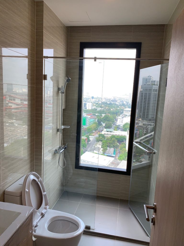 a bathroom with a glass shower door and a window