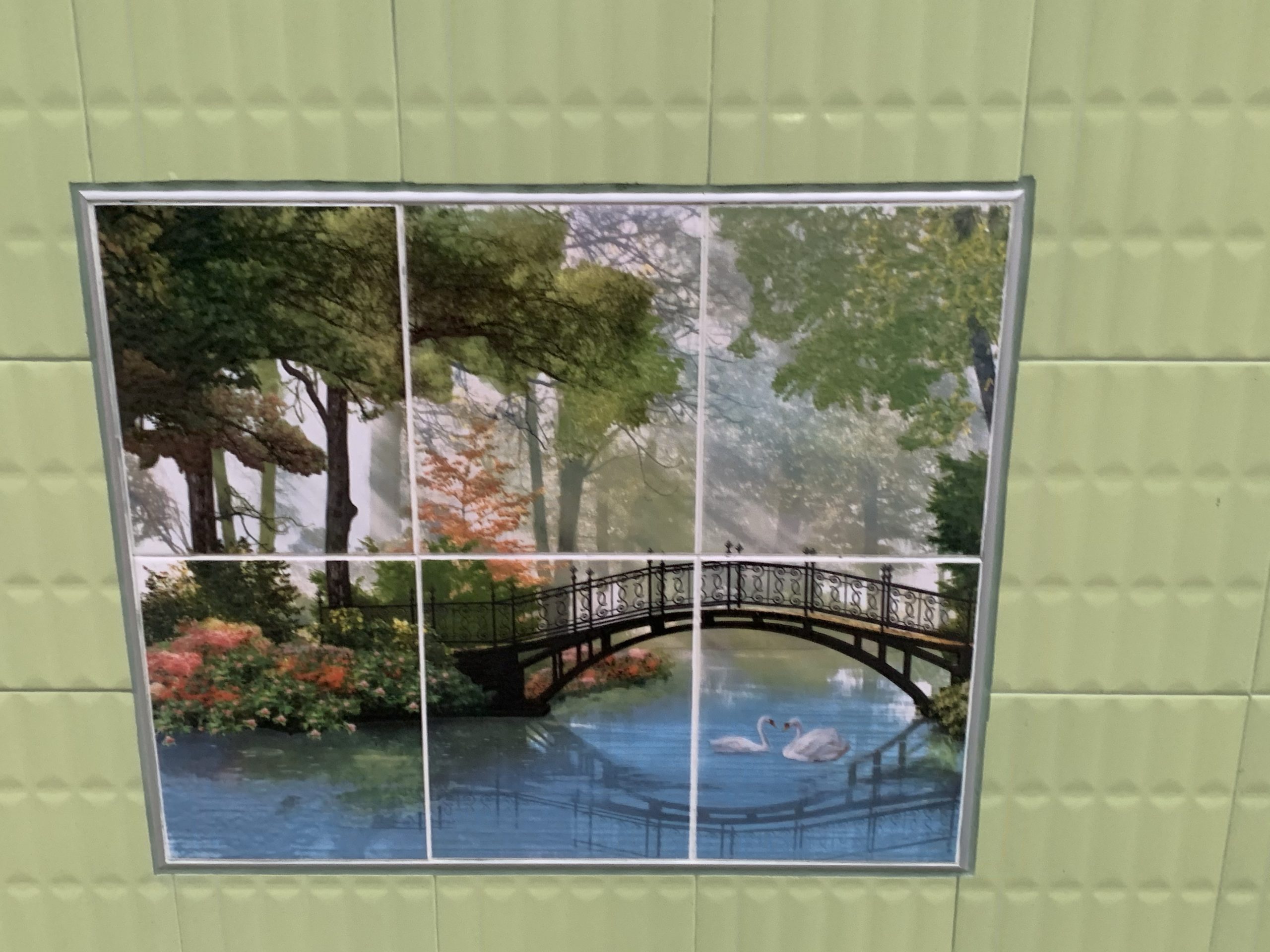 a tile wall with a bridge and swans