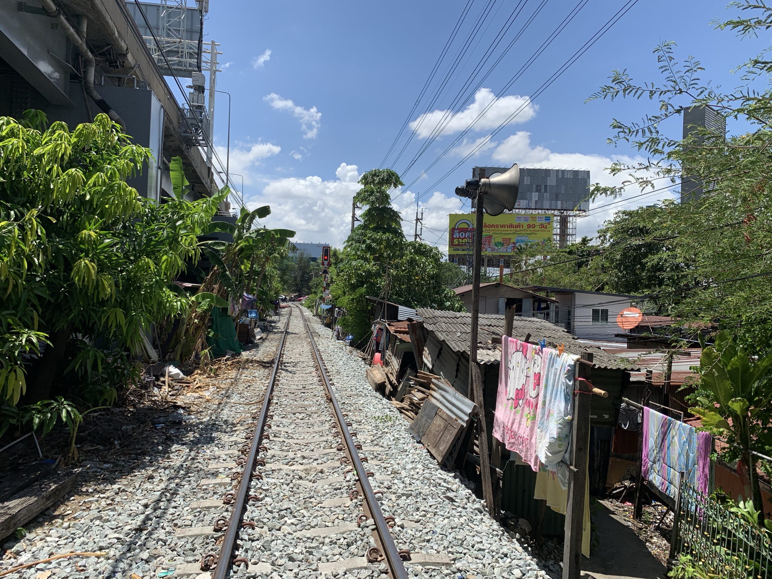 train tracks between buildings with clothes on the side