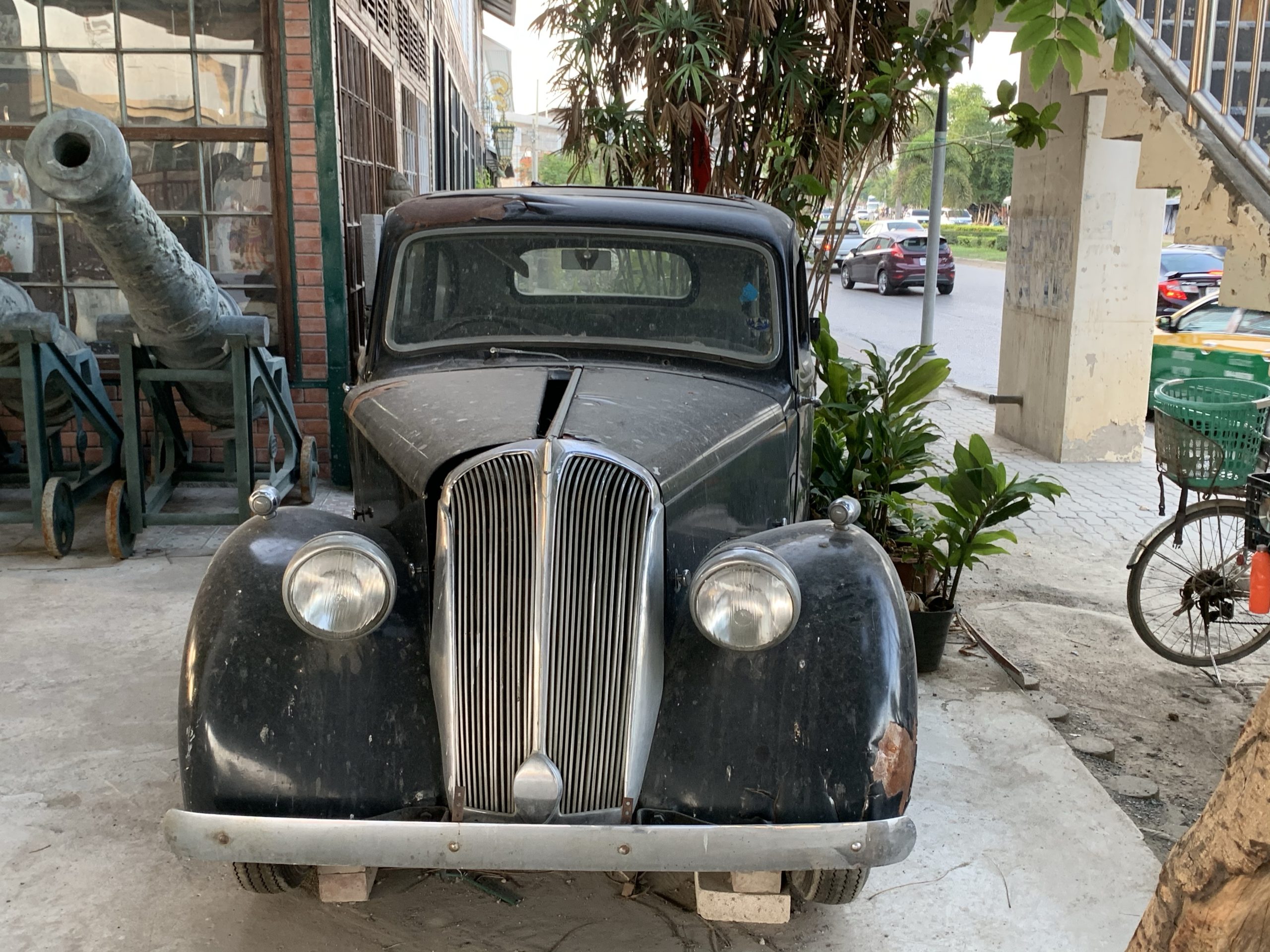 an old black car parked on the side of a road