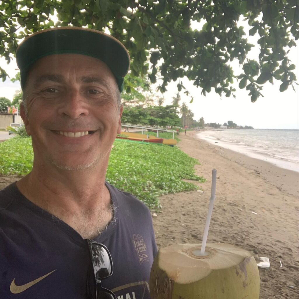 a man holding a coconut with a straw in his hand