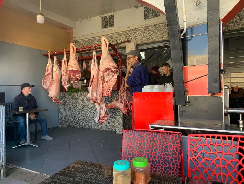 a group of people sitting in a chair in front of a butcher shop