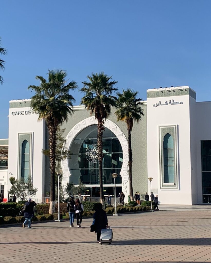 a building with palm trees and people walking in front of it
