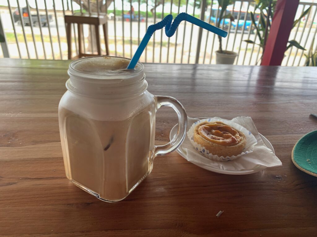 a glass mug with a straw and a pastry on a table