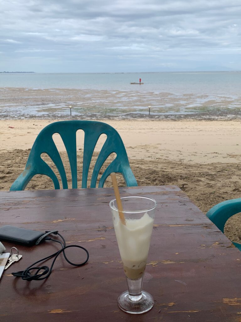 a table with a drink on it and a beach in the background