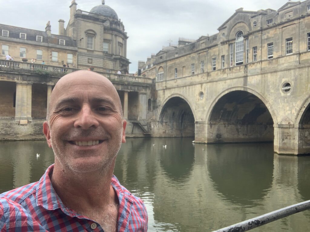 a man taking a selfie in front of a bridge