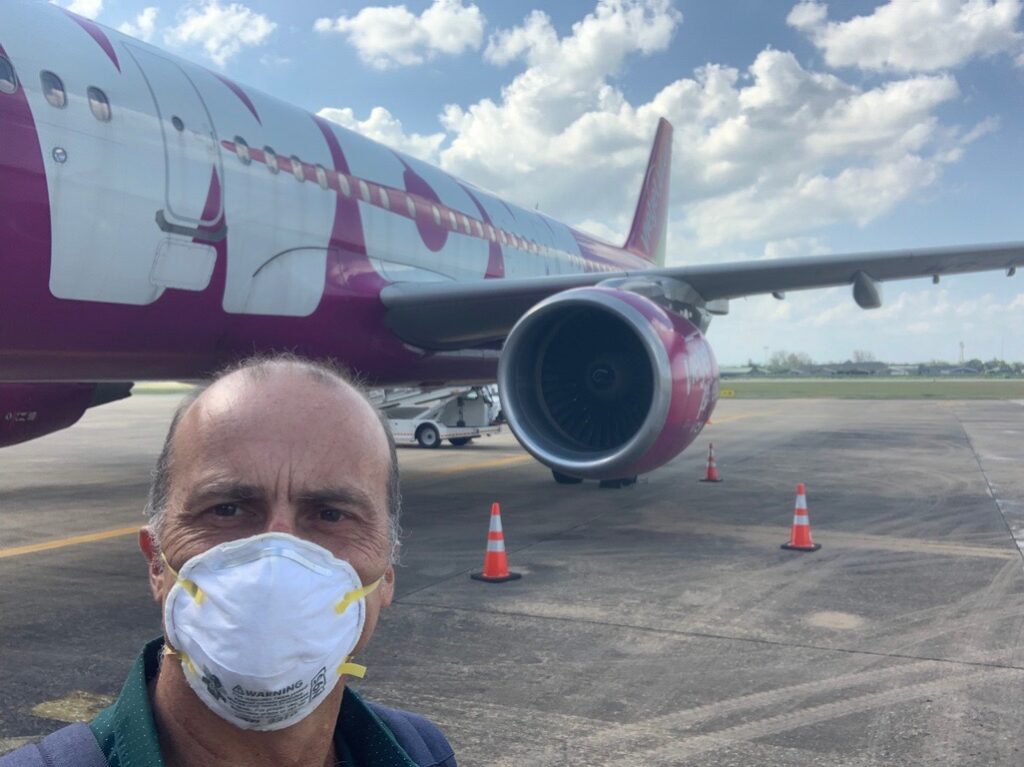 a man wearing a face mask in front of an airplane