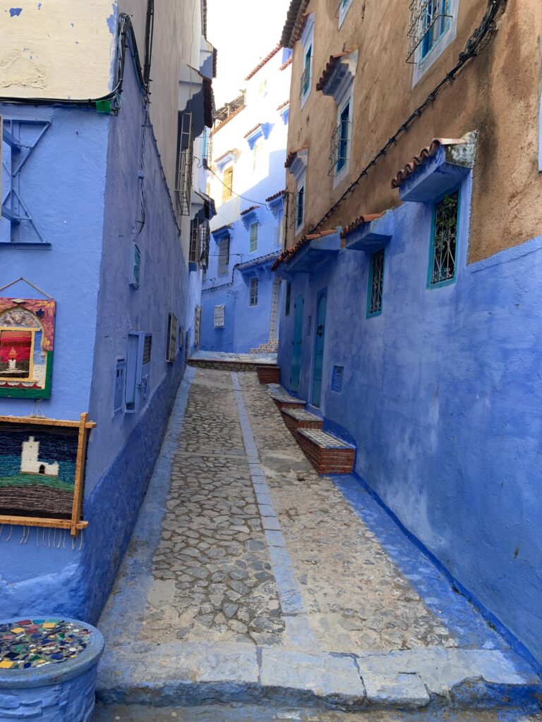 a blue painted alleyway with a stone walkway