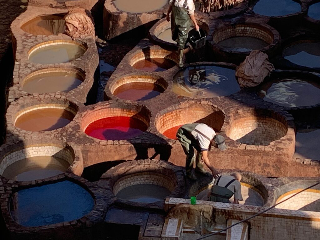 a group of men working in large round containers with colored liquid
