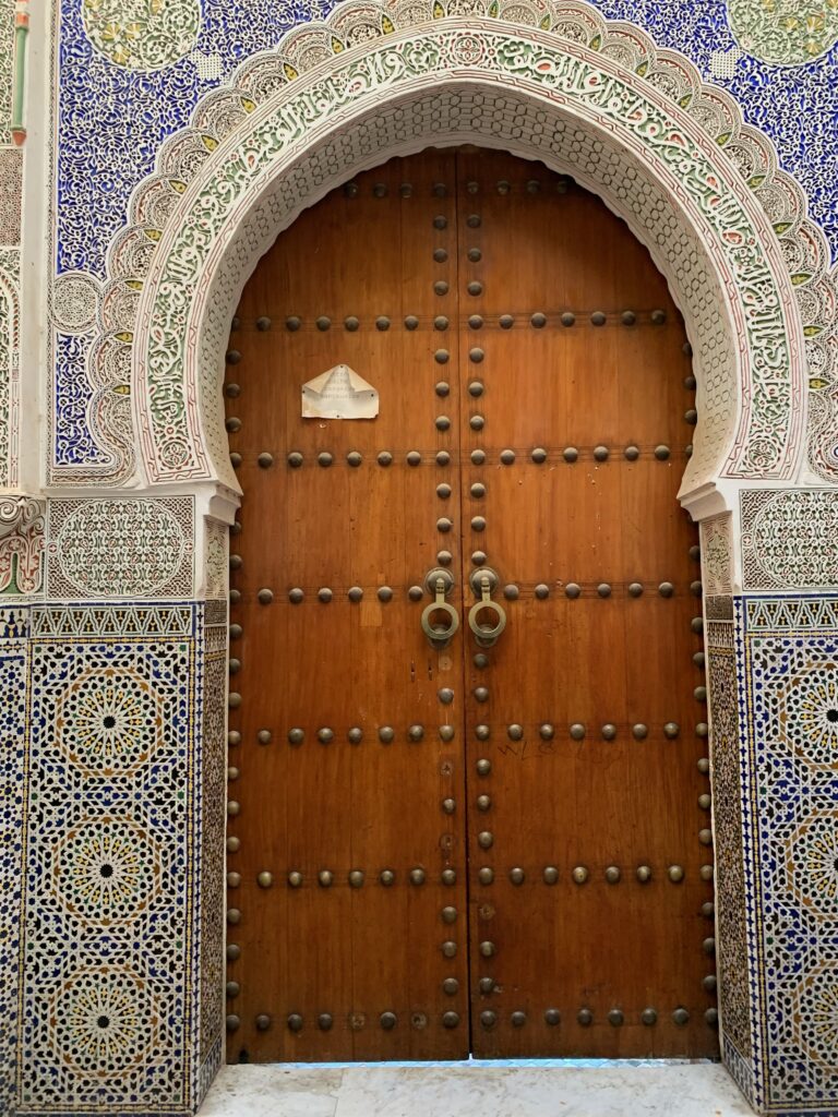 a wooden door with ornate tile and a paper on it