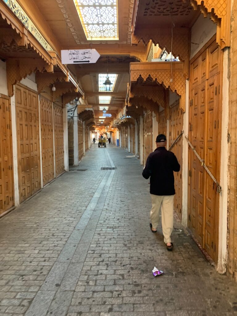 a man walking down a narrow street with wooden doors