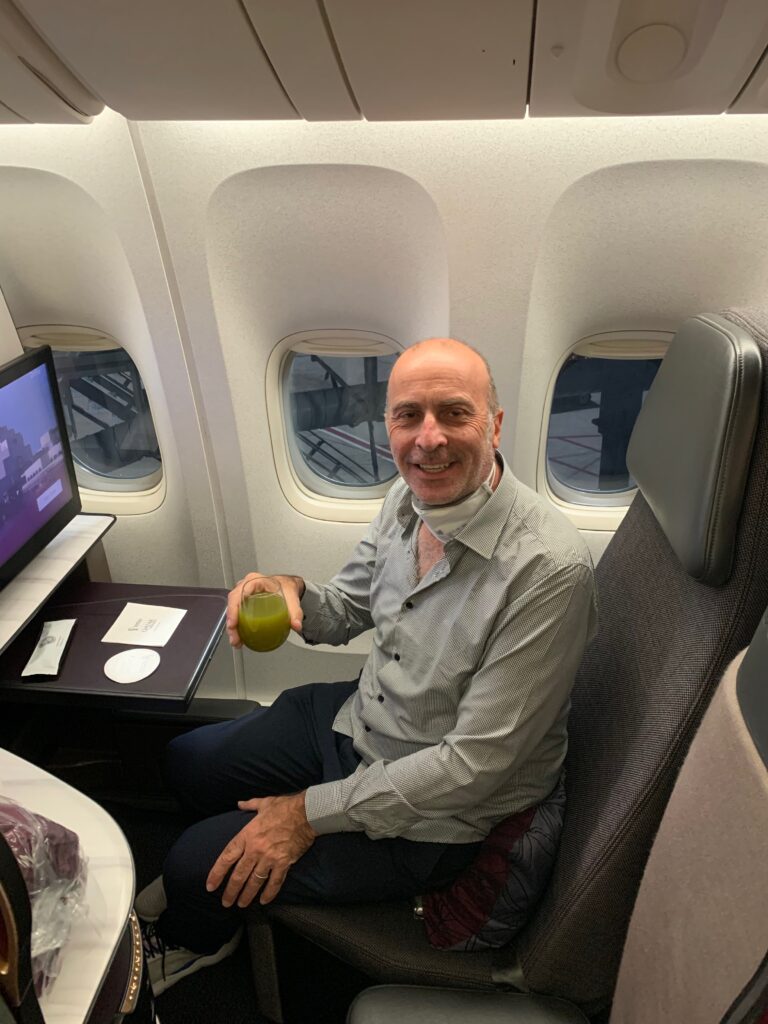 a man sitting in an airplane with a green drink