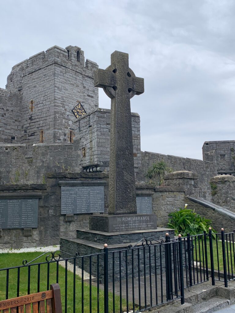 a stone cross in front of a castle