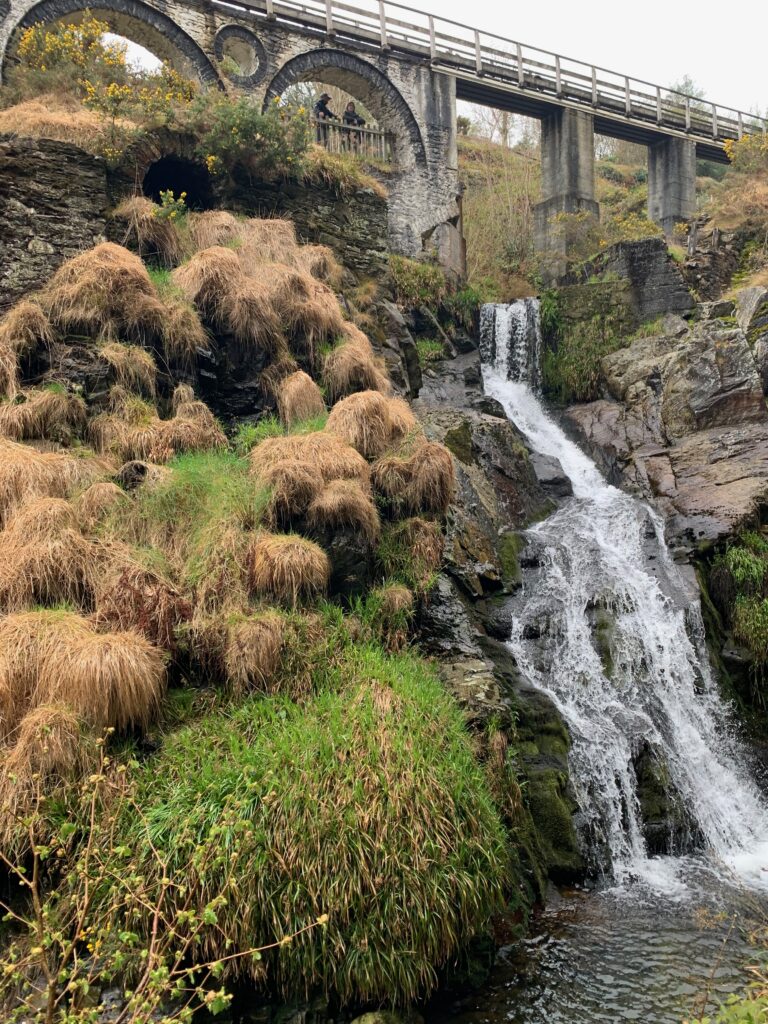 a waterfall next to a bridge