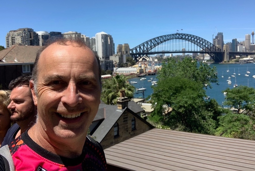 a man taking a selfie with a bridge in the background
