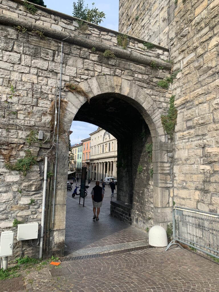 a stone archway with people walking in the background