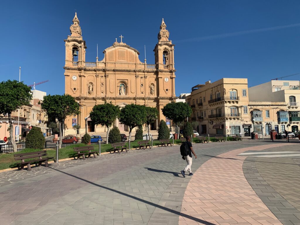 a man walking on a sidewalk in front of Palermo Cathedral