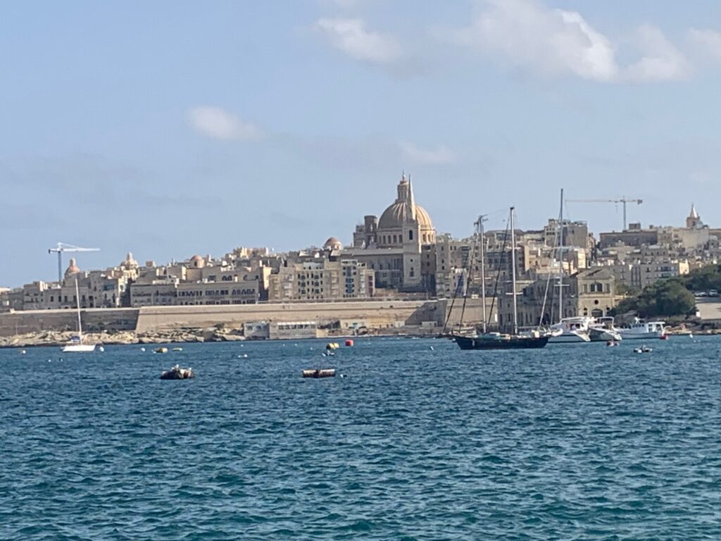 a body of water with boats and buildings in the background with Valletta in the background