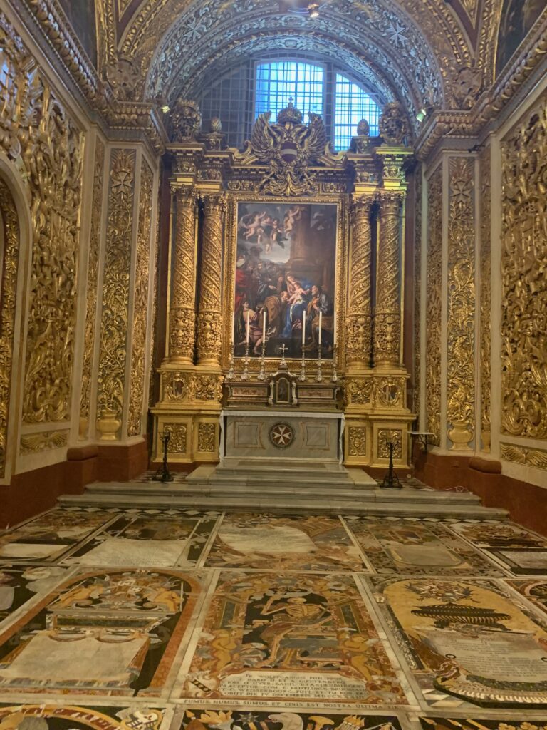 a gold ornate room with a painting on the wall
