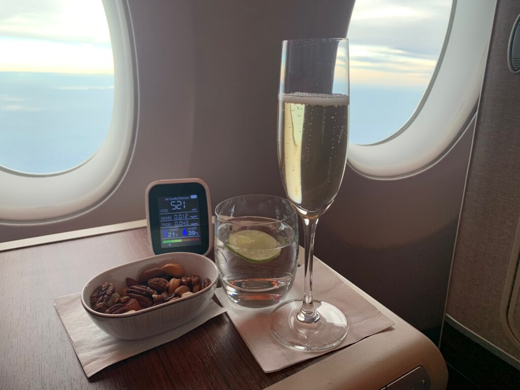 a glass of champagne and a bowl of nuts on a table with windows