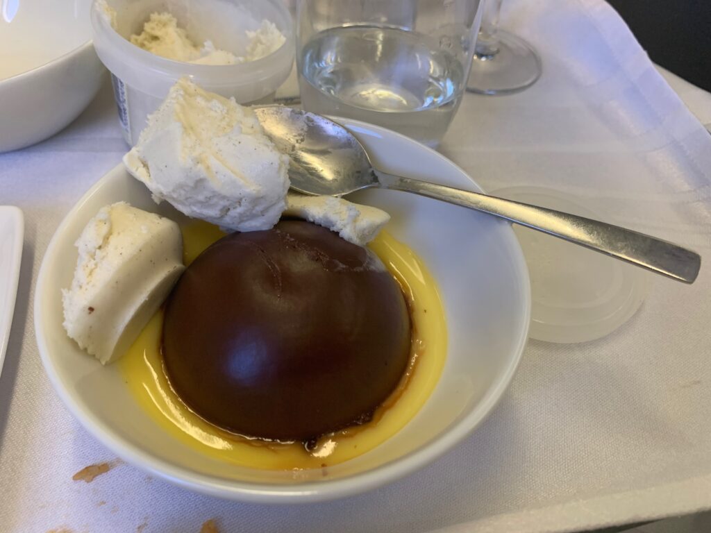 a bowl of dessert with a spoon and a glass of water
