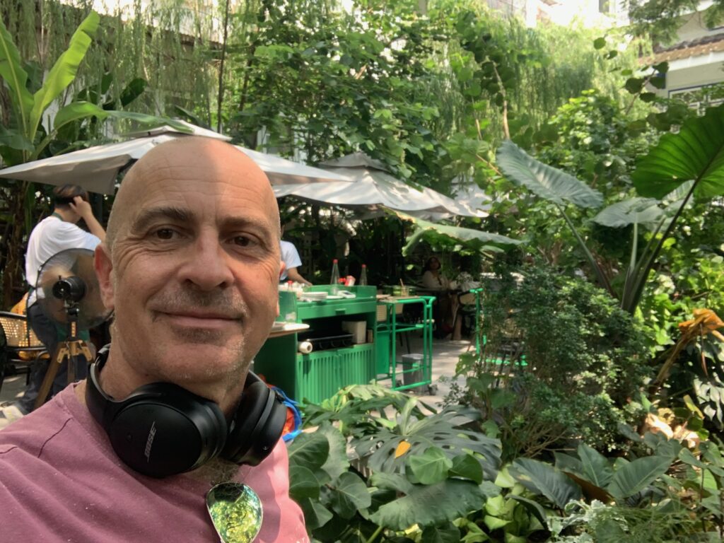 a man with headphones around neck in a garden
