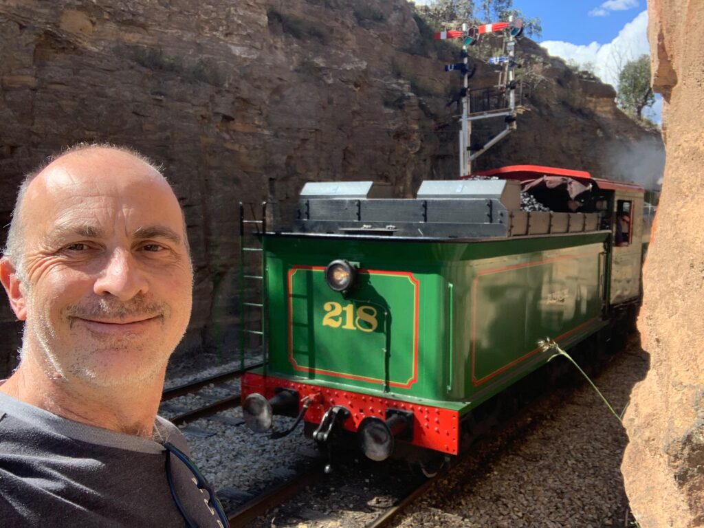 a man taking a selfie in front of a green train