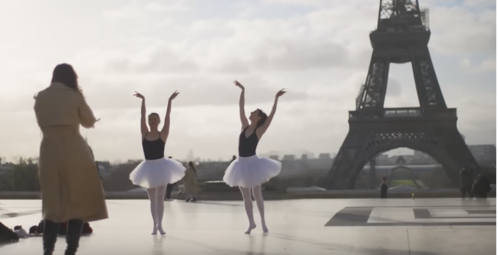two women in tutu dancing in front of the eiffel tower