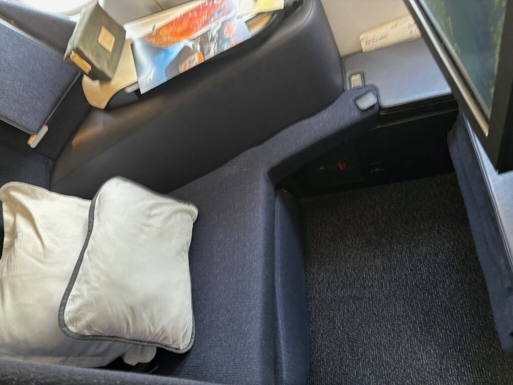 a seat with a pillow and a book on the side of it