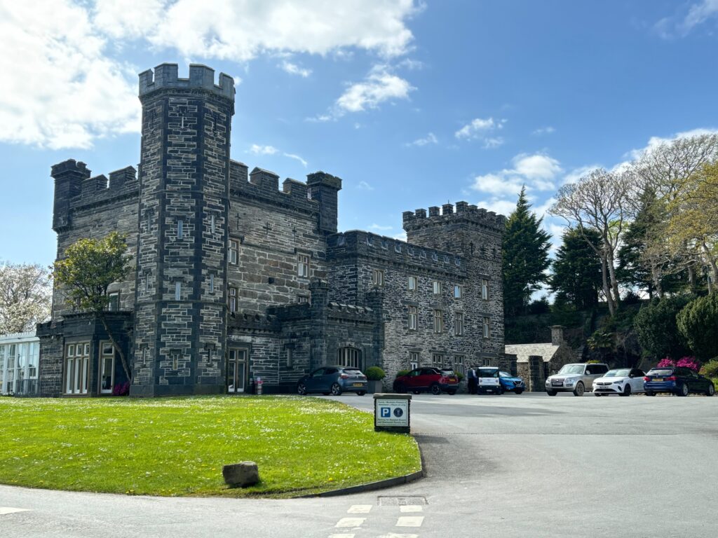 a stone castle with a parking lot and cars parked in front