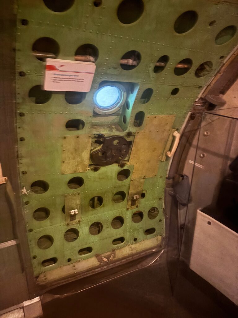 a green metal panel with holes and a round window