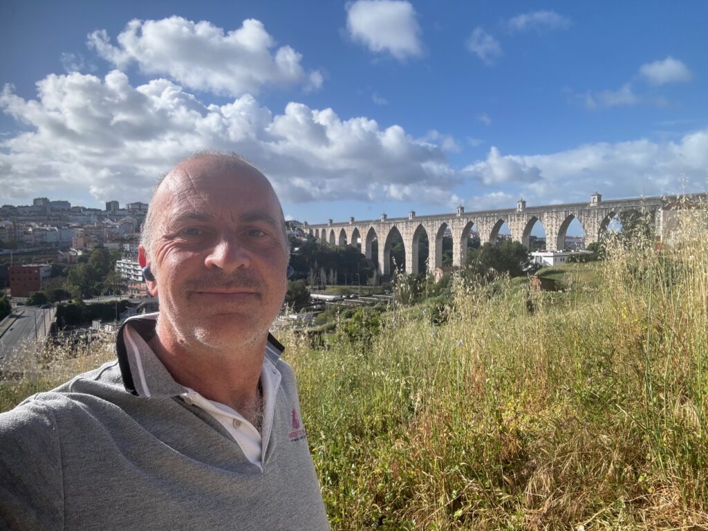 a man taking a selfie in front of a large stone bridge