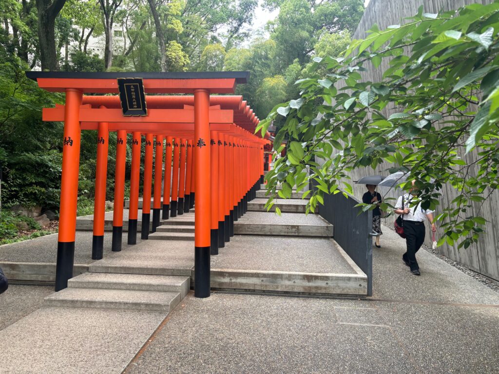 a group of orange pillars with black trim with Fushimi Inari-taisha in the background